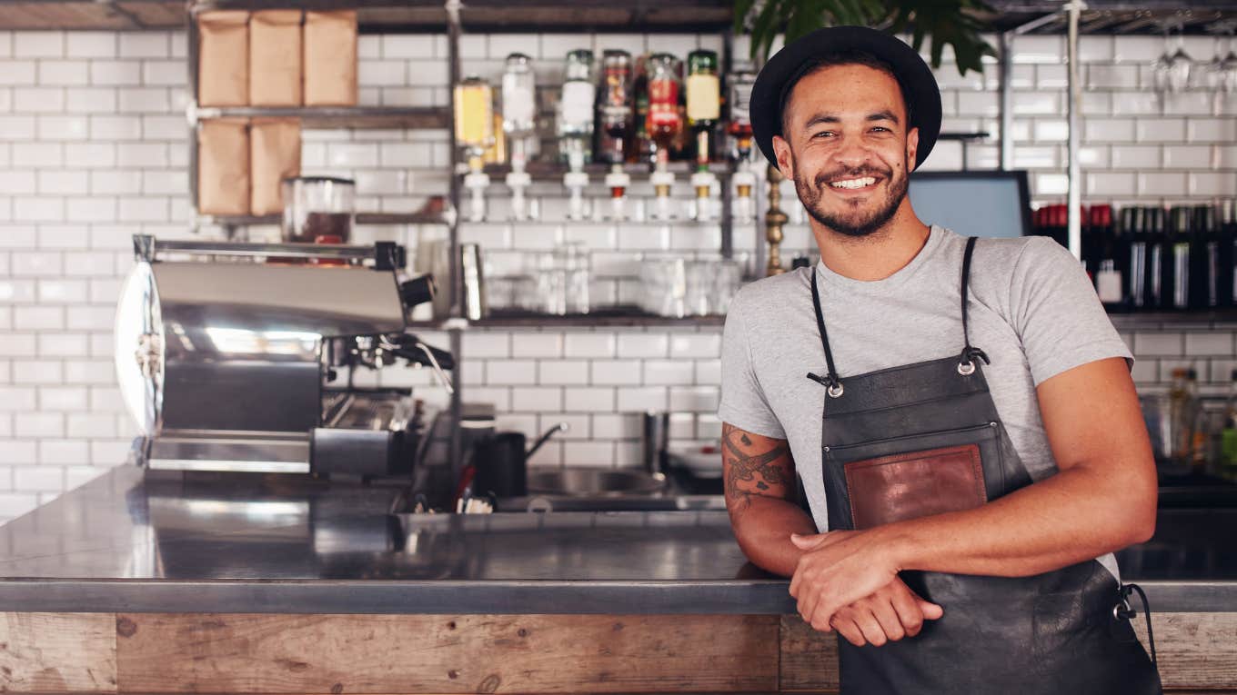 Coffee shop barista smiling behind the counter. 