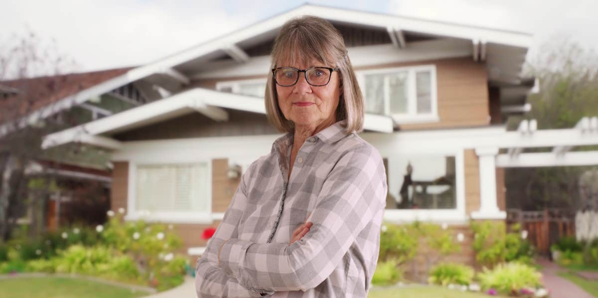 woman standing in front of house with arms folded