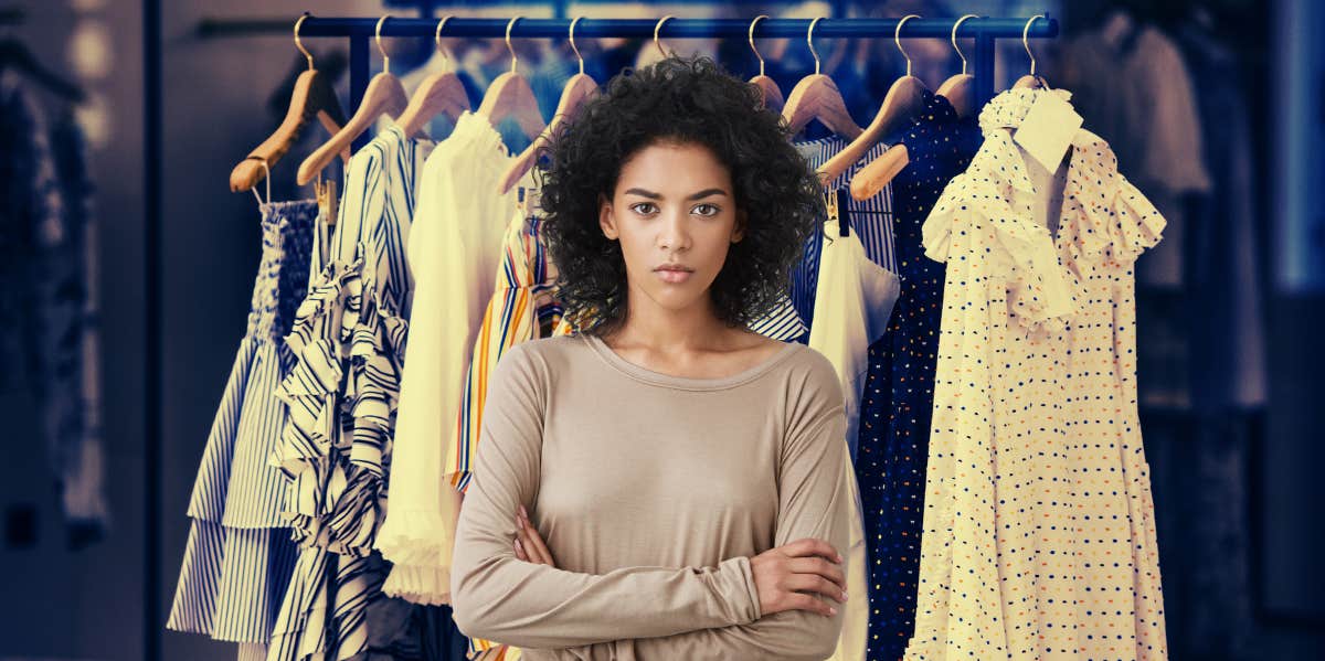 dresses hanging up on hangers, woman with arms crossed looking angry