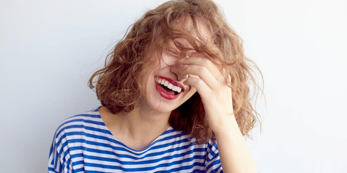 woman laughing with hand on face