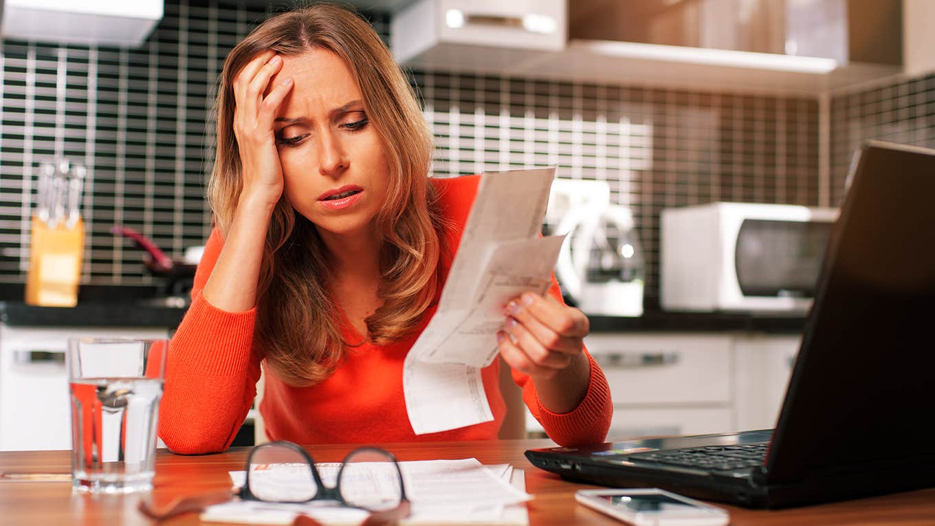 stressed young woman is doing banking and administrative work holding bills at home