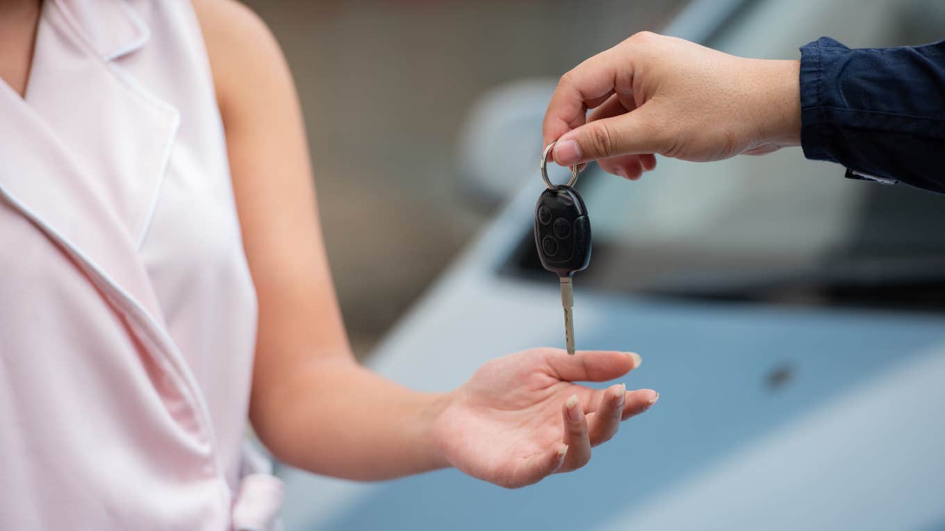 Lawyer Making $200K Explains Why She Drives A 14-Year-Old Vehicle car salesman handing woman set of keys