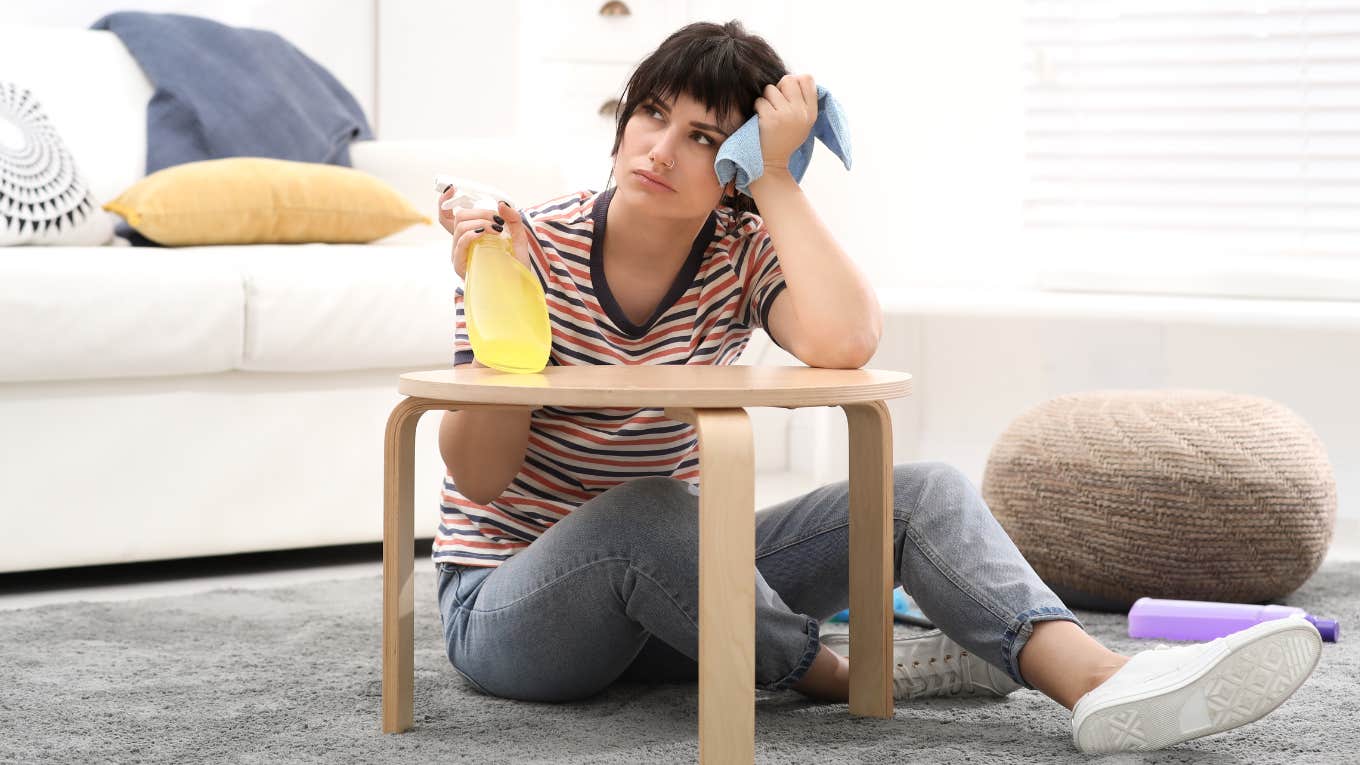 Woman sitting on the ground with cleaning supplies. 