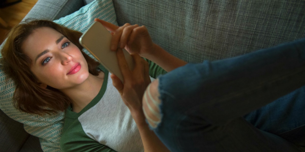 woman laying on the couch playing on phone