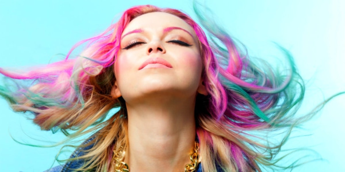 woman with colored hair blowing blue background