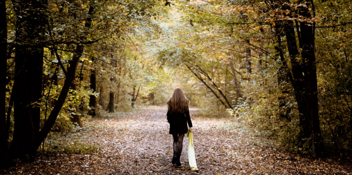 woman walking away in forest