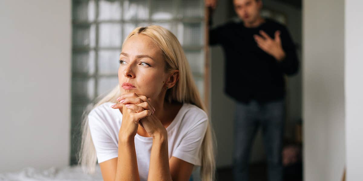 woman looking upset with man standing behind her 