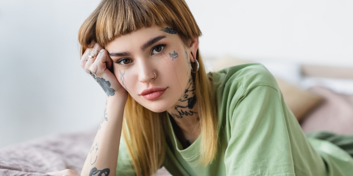 tattooed woman wearing green in bed