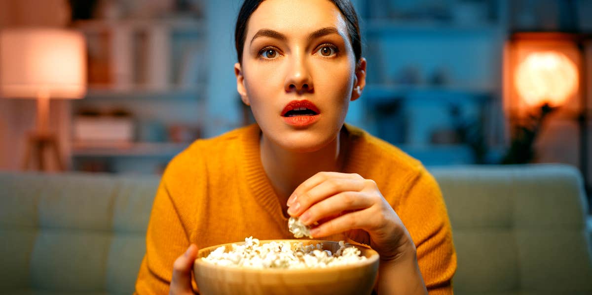 young woman watching Nicholas Sparks movies while eating popcorn