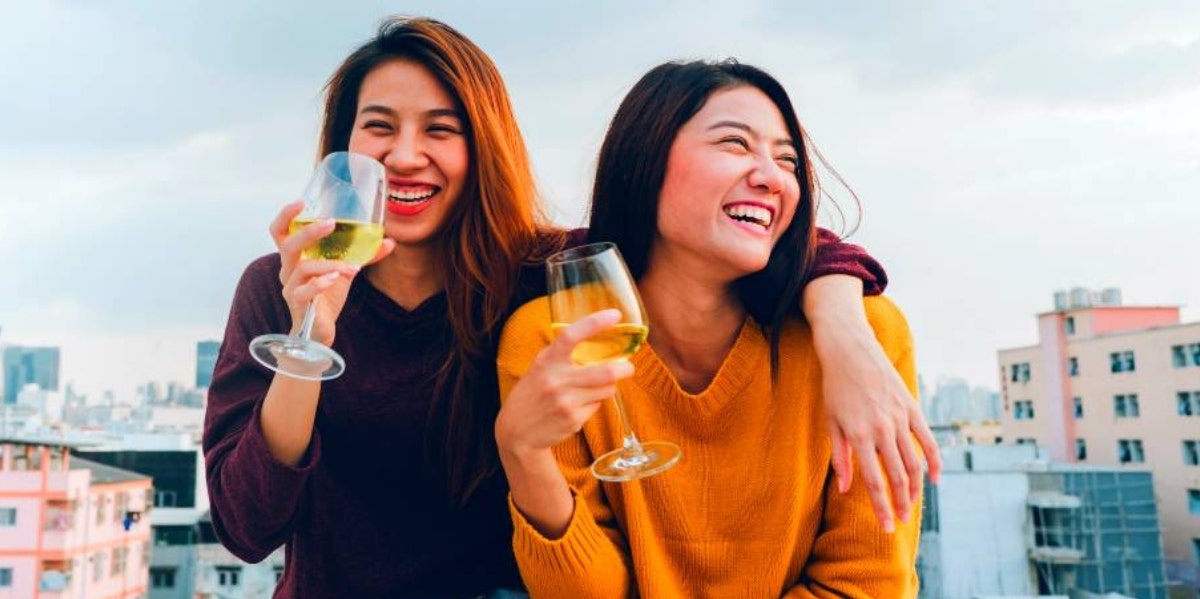 two women laughing and drinking