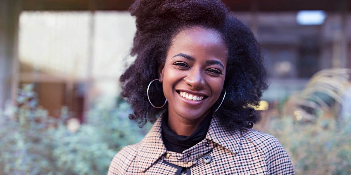 Confident woman outdoors looks at camera and smiles.