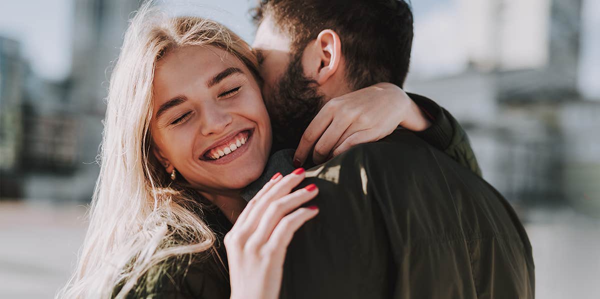 man and woman hugging while woman smiles 