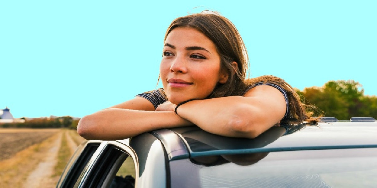 smiling woman looking out of car window thinking of her long distance relationship