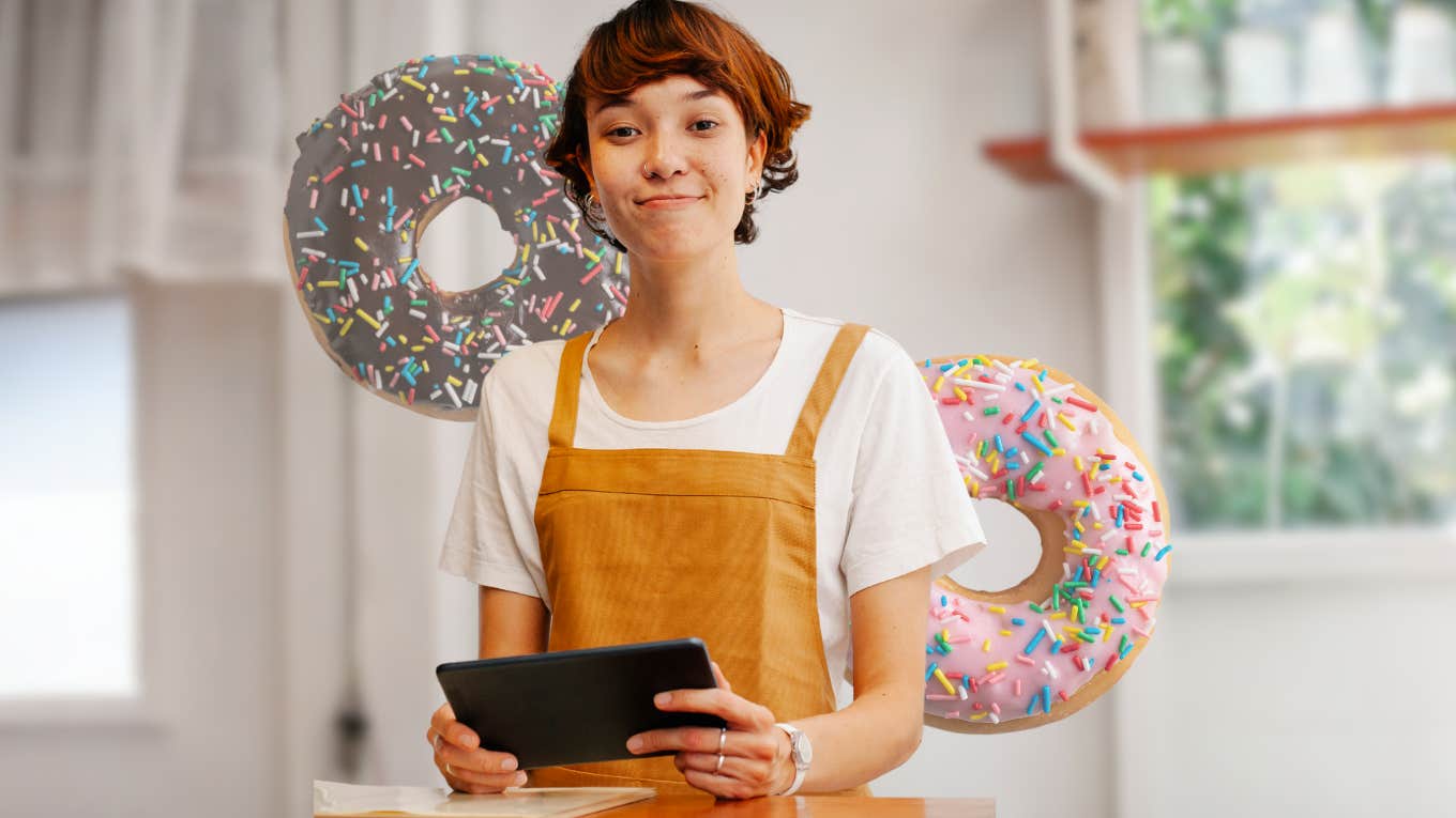 Long Island Bakery Accused Of Selling ‘Dunkin’ Donuts’ Labeled As Vegan & Gluten Free Bakery worker standing in front of donuts