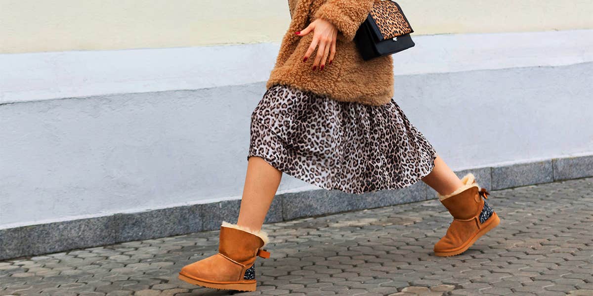 woman in skirt and boots walking on sidewalk