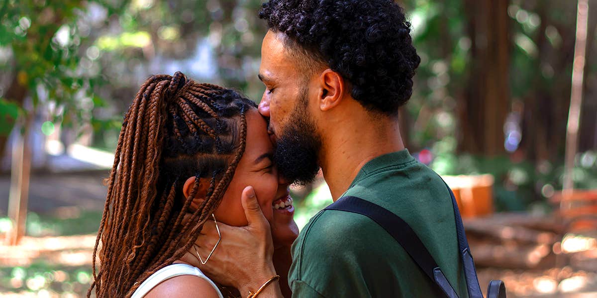 man kissing woman's forehead