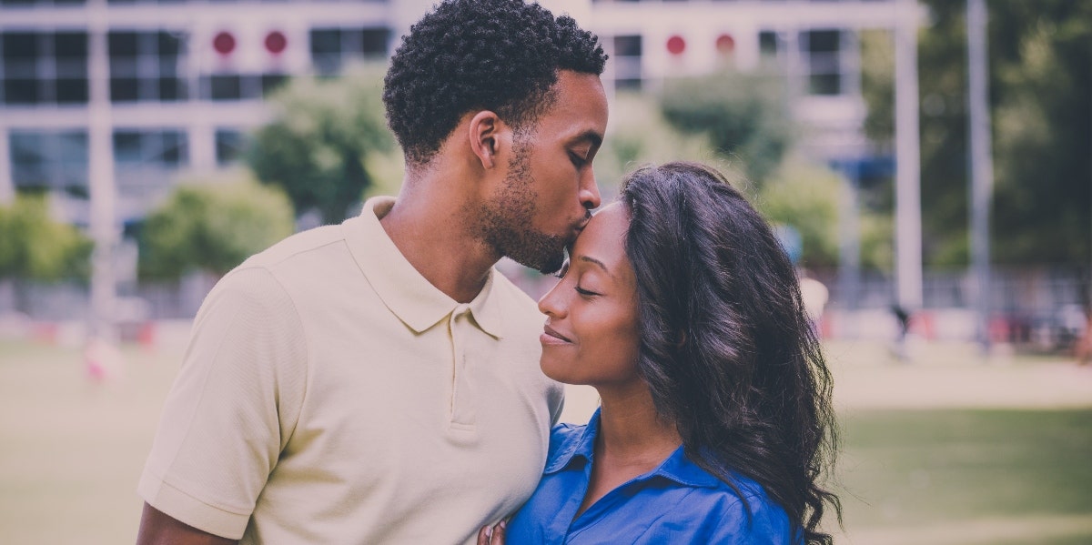 man kissing a woman on her forehead