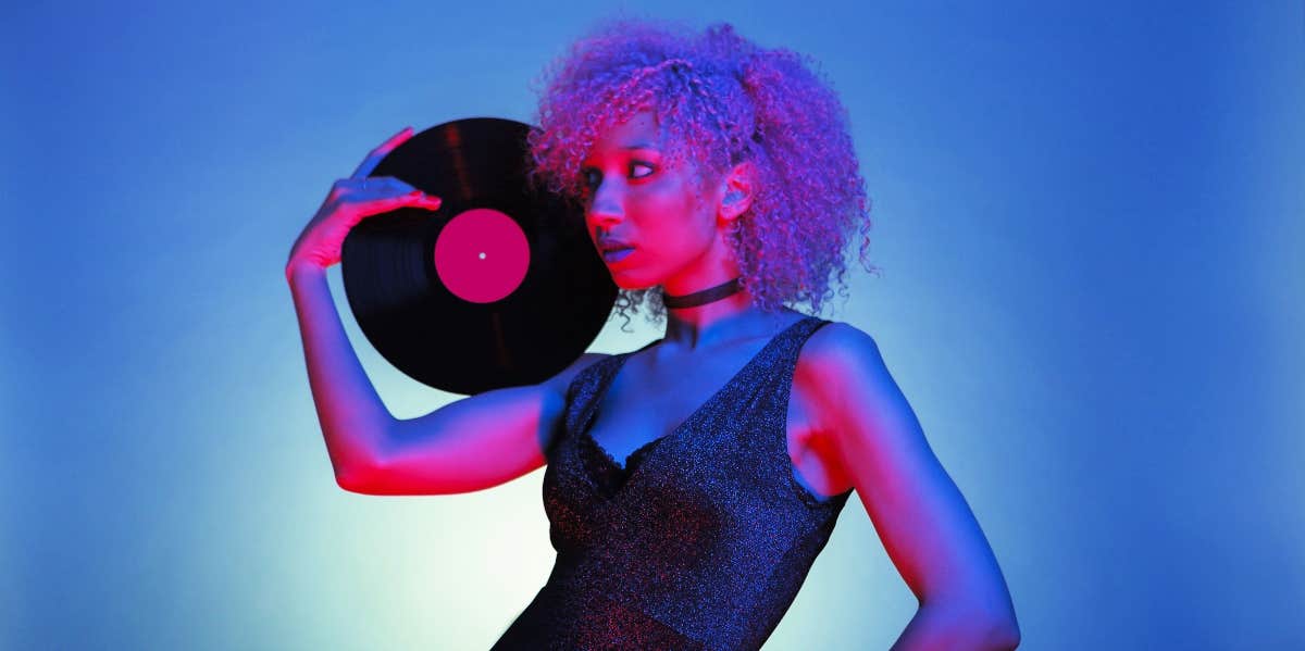 woman dressed in 80s clothes holding a vinyl album