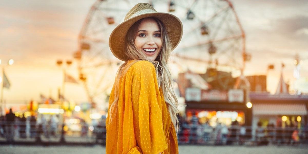 happy woman standing in front of a ferris wheel