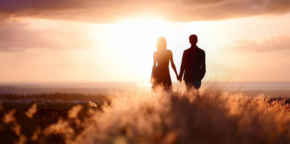 woman and man holding hands in sunset