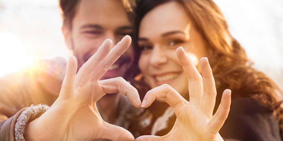 man and woman making heart with their hands