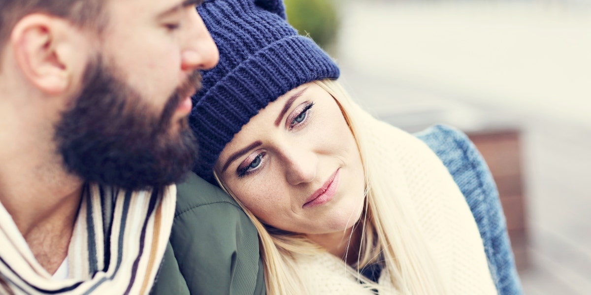 sad woman laying her head on man's shoulder