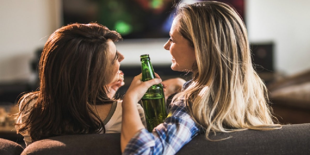 two women laughing with beers in hand