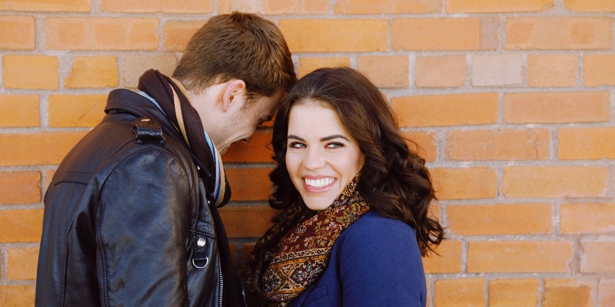 happy couple standing by brick wall