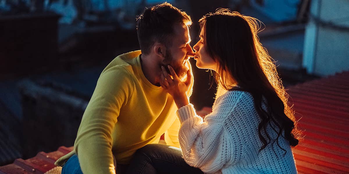 woman kissing man in dim lighting