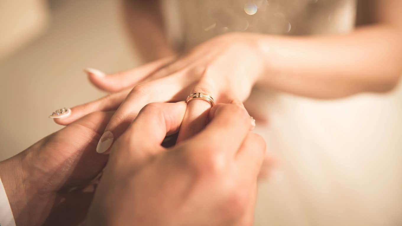 groom putting ring on bride's finger