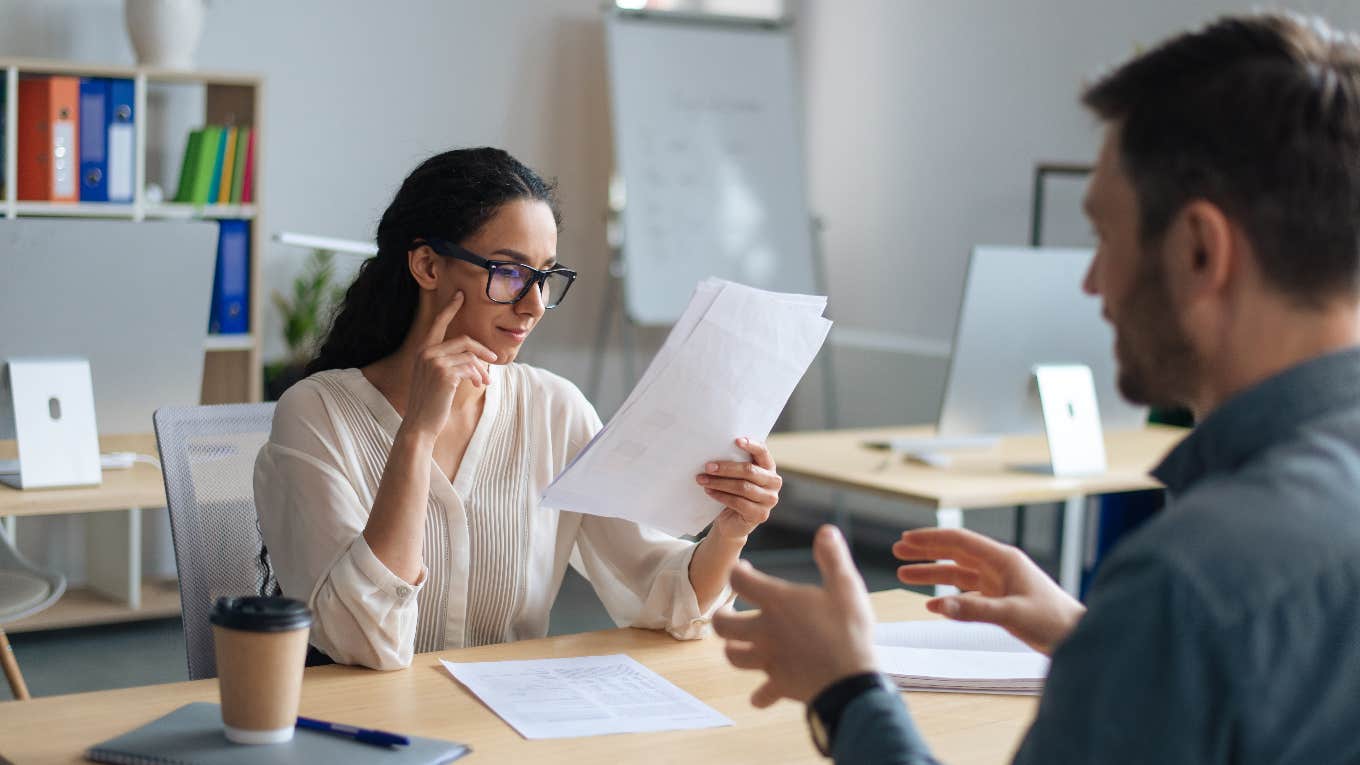 woman reading man's resume during job interview