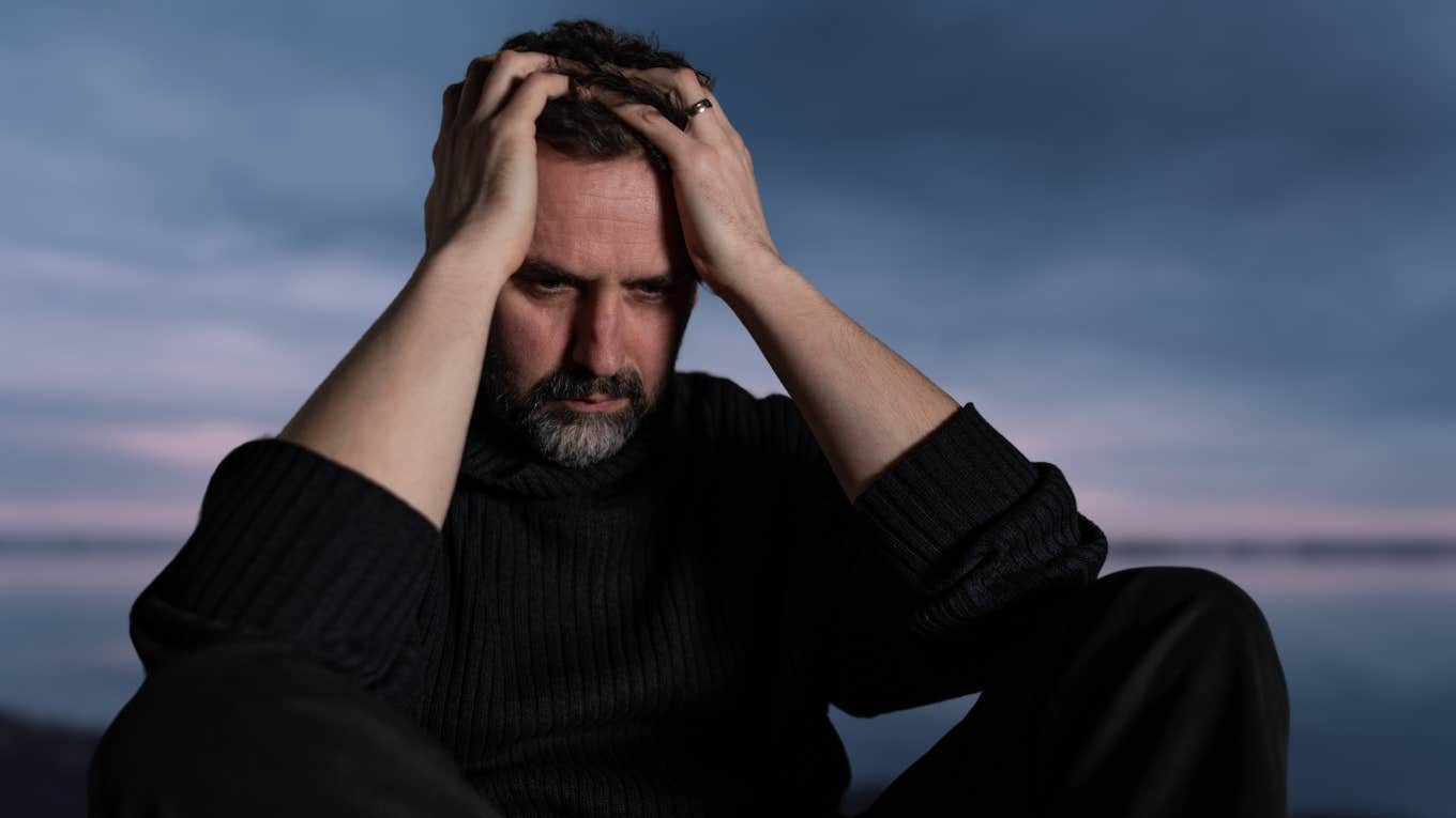 Man looking upset in front of a dreary background. 