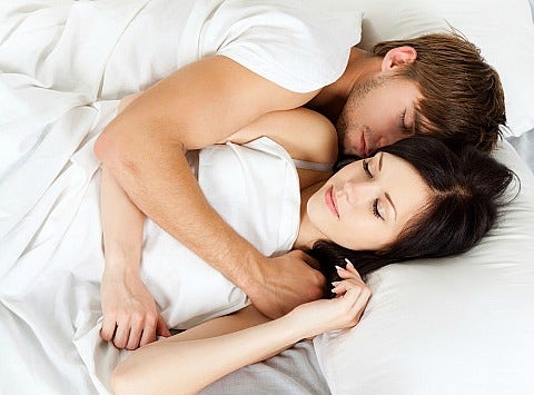 man and woman cuddling in bed