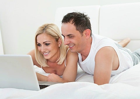 man and woman looking at laptop in bed man and woman looking at laptop in bed