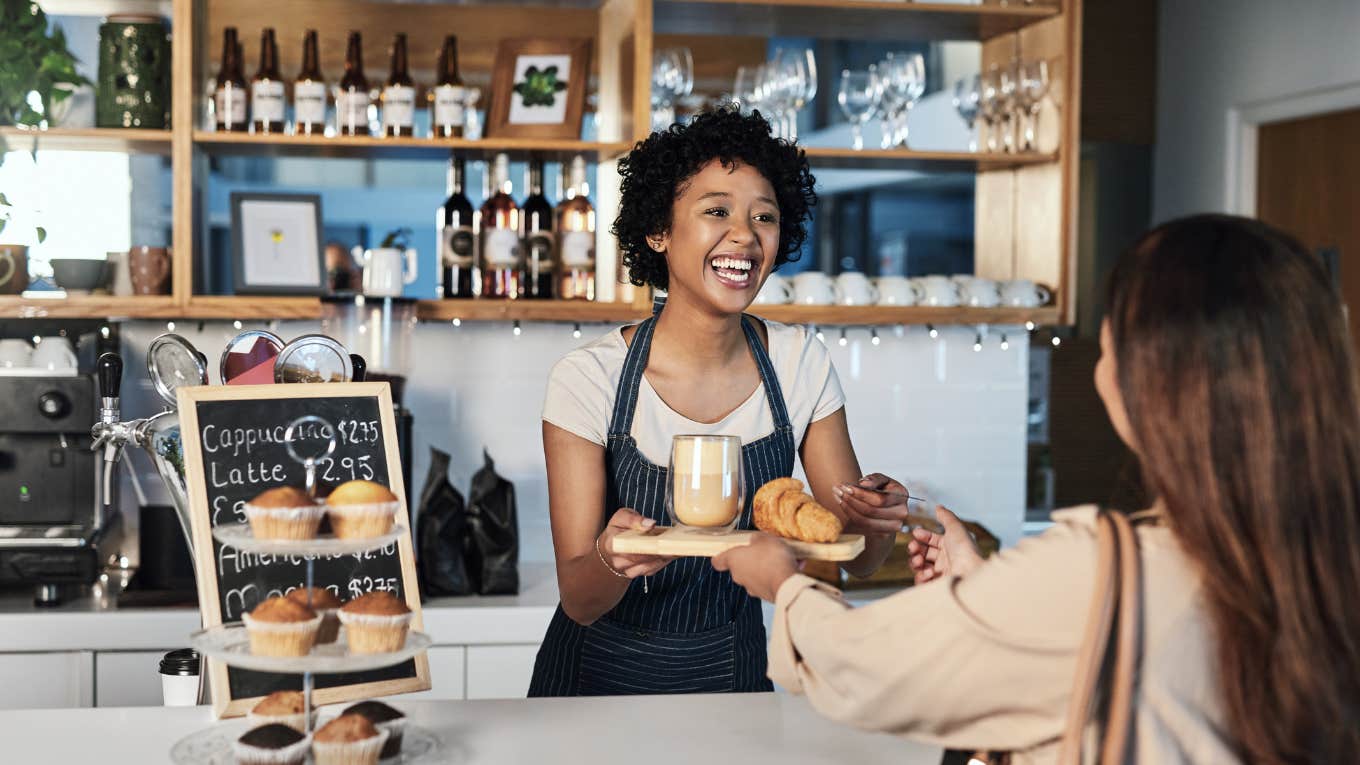 barista serving customer food at cafe