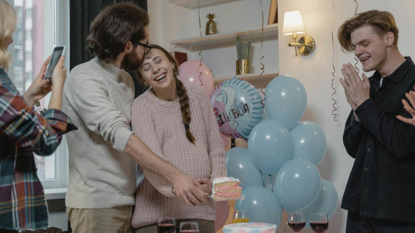 couple cutting cake at gender reveal party with friends