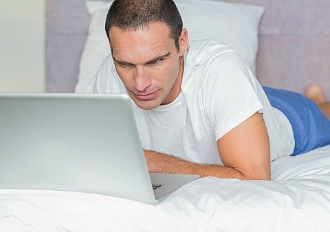 man looking at laptop in bed