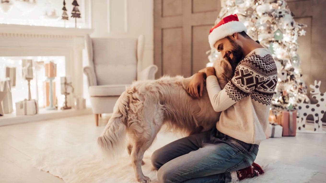 Man Makes Single Christmas Cards To Let Friends And Family Know He's Still Not Married man in Santa hat hugging dog