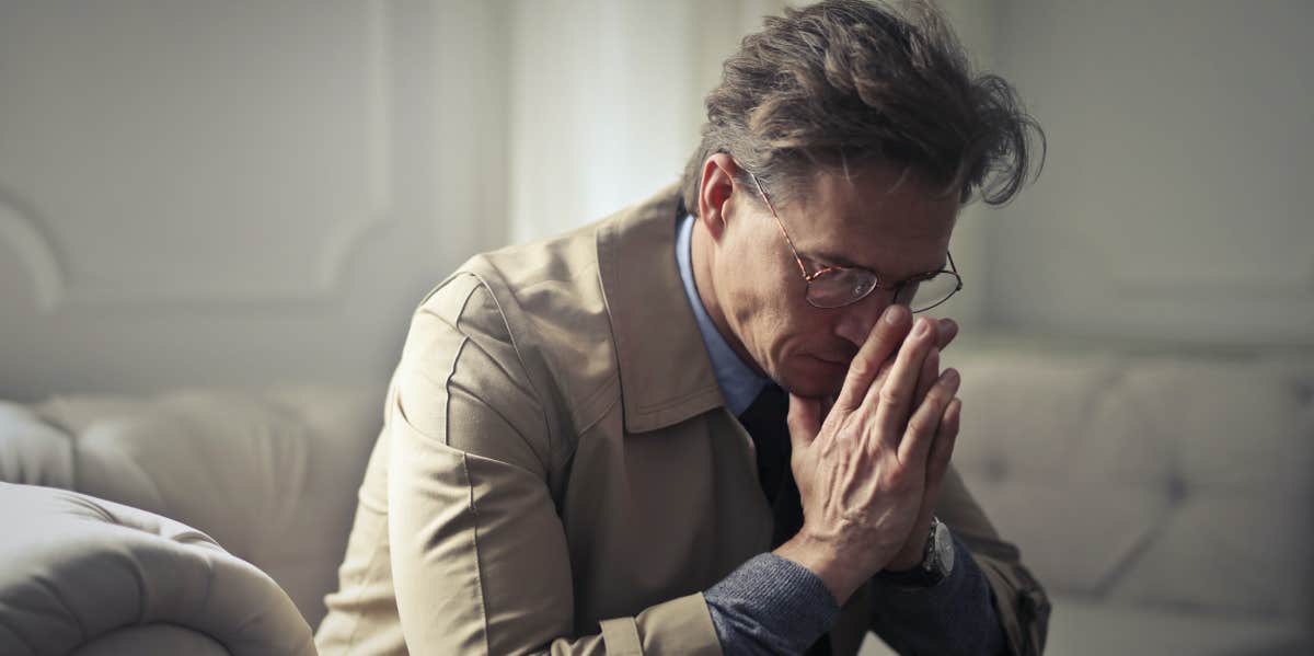 Man looking sad and thinking while sitting on a couch