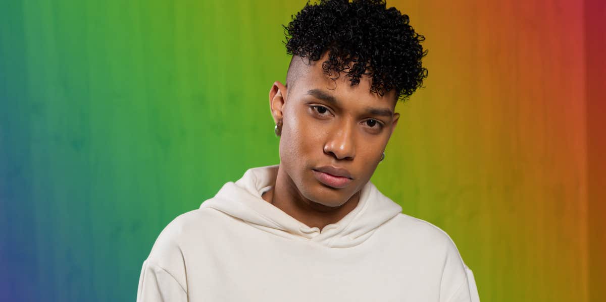 Man Claims He's Straight Even Though He Sleeps With 'Guys Once Or Twice A Week' Man looking ahead, rainbow background