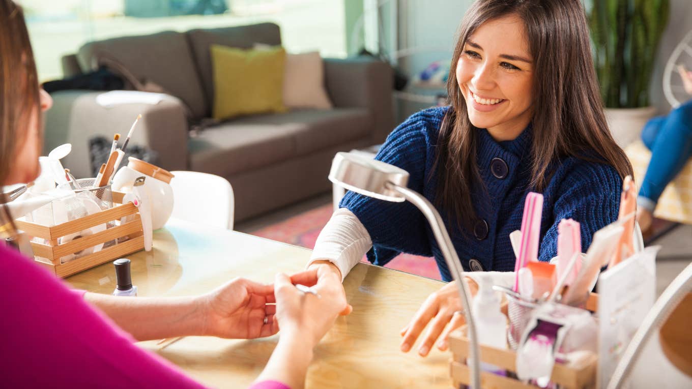 young woman getting her nails done by a manicurist in a beauty salon