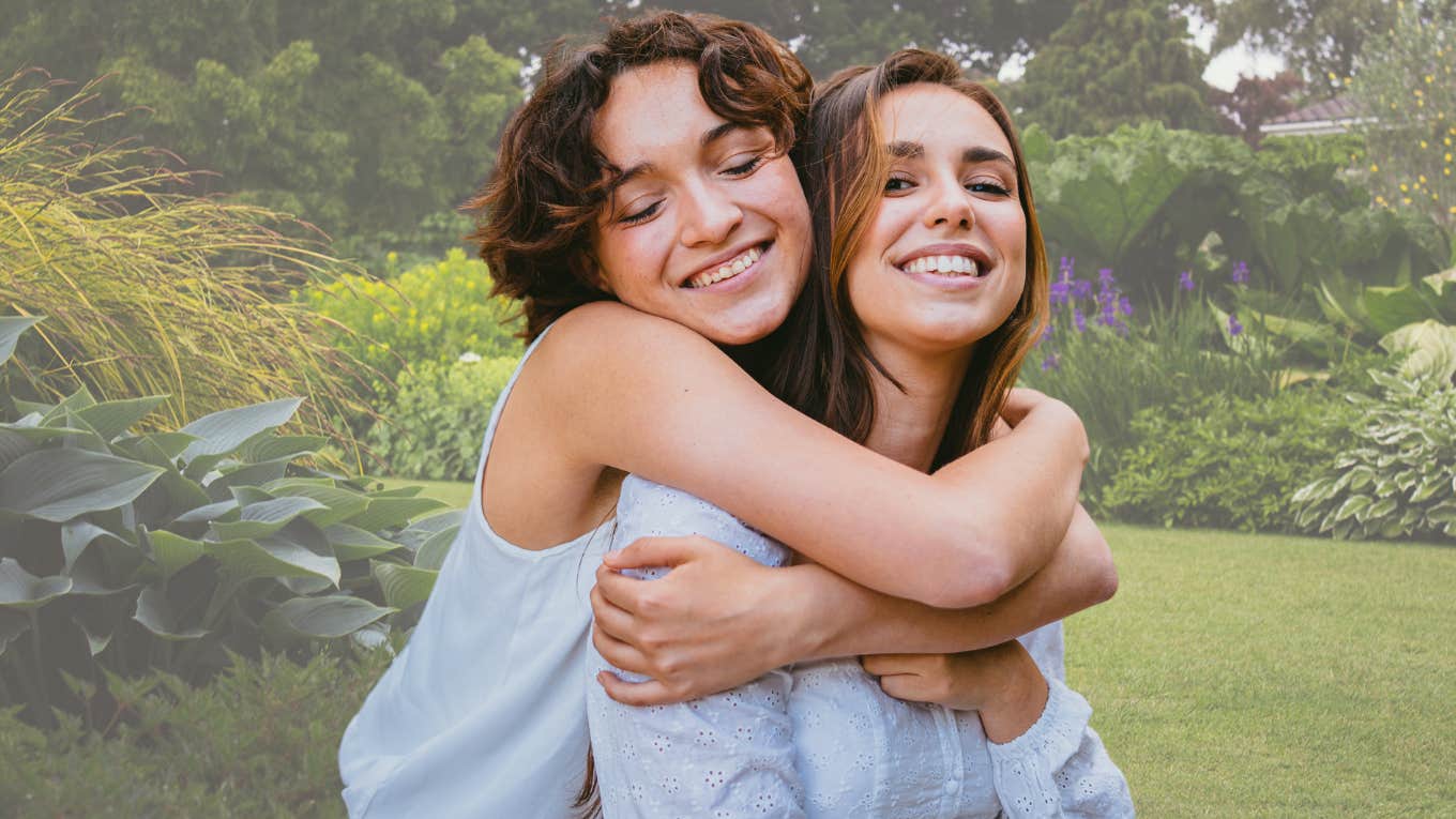 Two sisters hugging each other and smiling. 