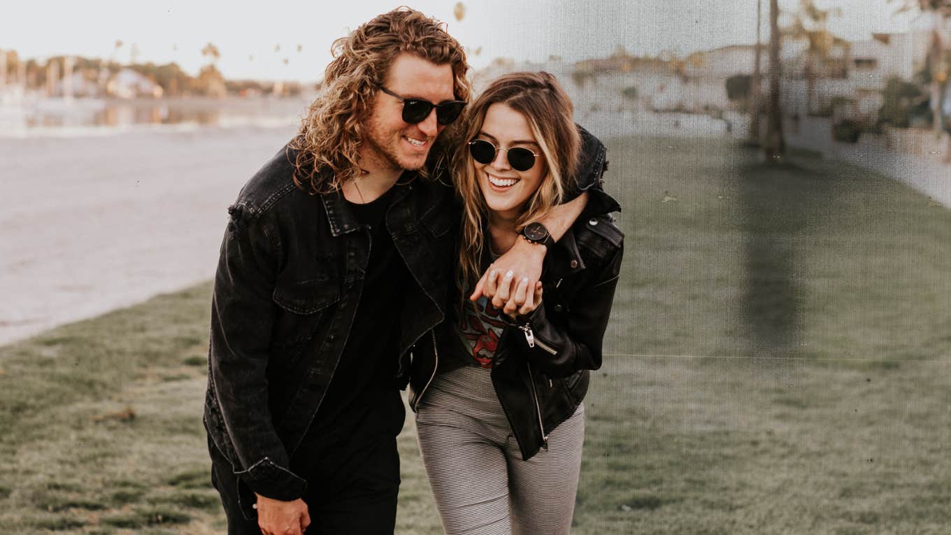 Couple with arms around each other walking outside laughing 