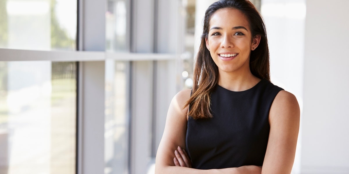 professional woman standing by window with arms crossed