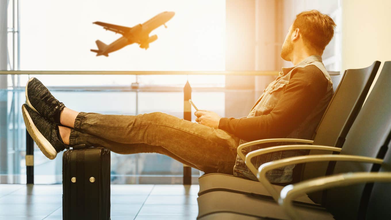 Man's Neck Pillow Travel Hack Will Have You Sleeping Like A Baby On Your Next Flight man sitting at the airport