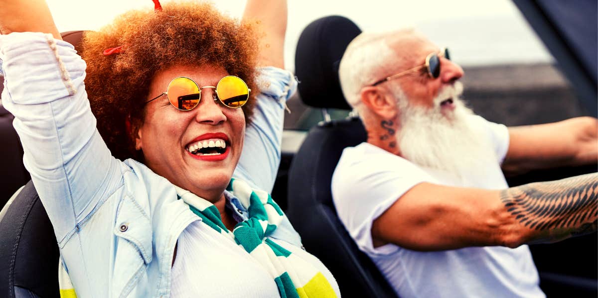 older couple having fun driving in their car with the top down