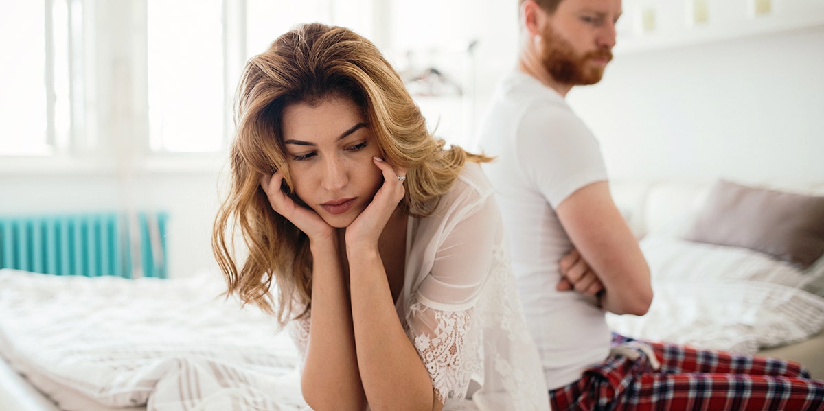 woman looking distraught with husband in background