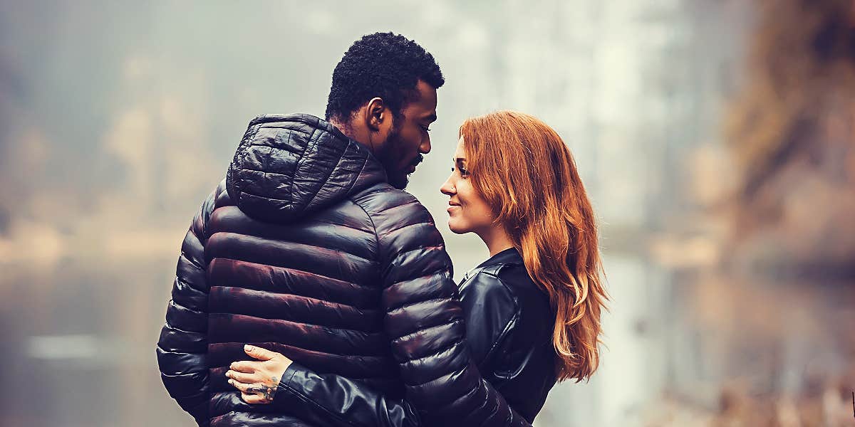 mixed race couple looking lovingly at one another in front of waterfall