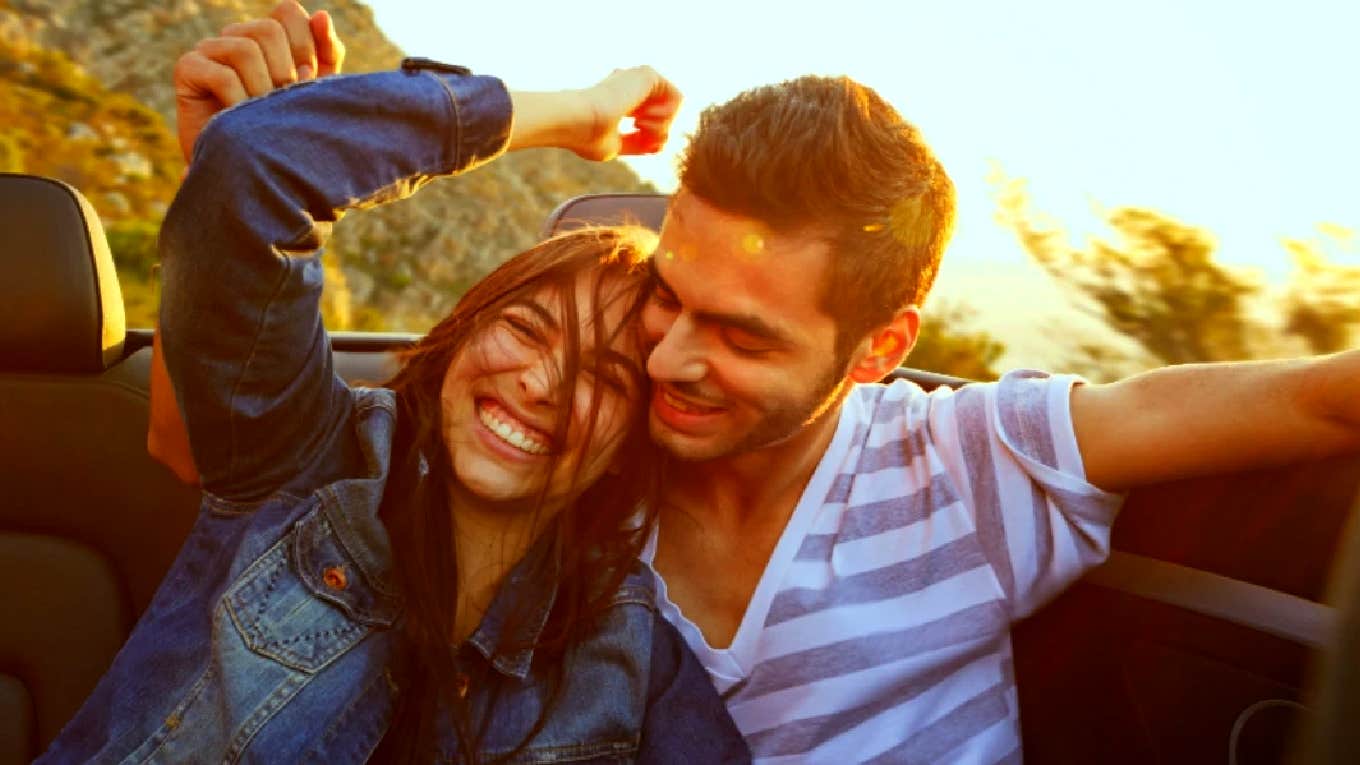 couple laughing in a convertible driving