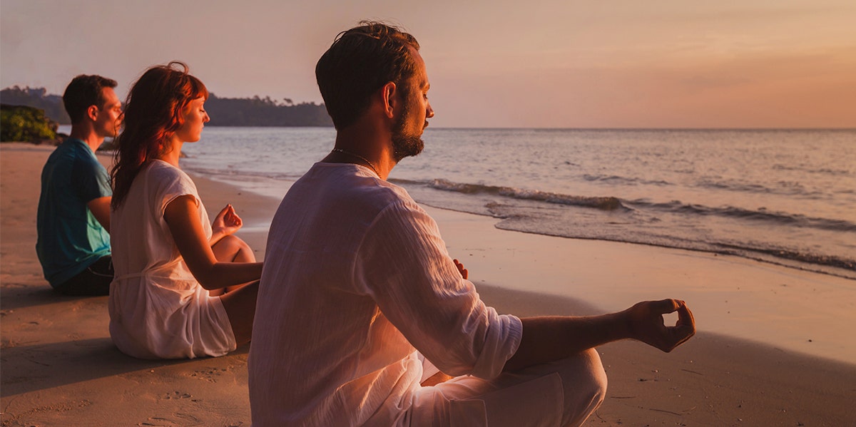 Men and women meditating on the beach